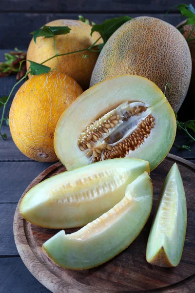 Rijpe meloenen met groene bladeren op houten tafel close-up — Stockfoto