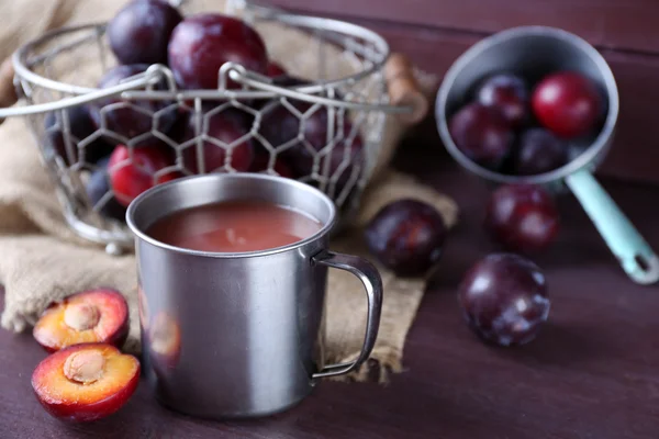 Läckra plommon juice med frukter på bordet på nära håll — Stockfoto