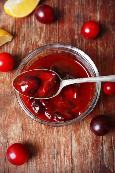 Gustosa marmellata di prugne fatta in casa in piattino di vetro su sfondo di legno — Foto Stock