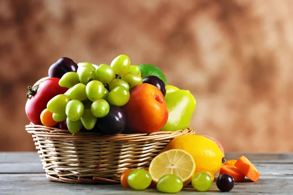 Högen av färsk frukt och grönsaker i korg på träbord nära håll — Stockfoto