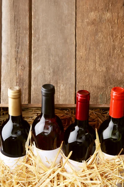 Boîte avec paille et bouteilles de vin sur fond en bois — Photo