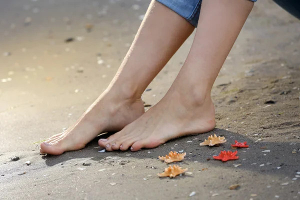 Жіночі ноги з морськими зірками на піщаному пляжі — стокове фото