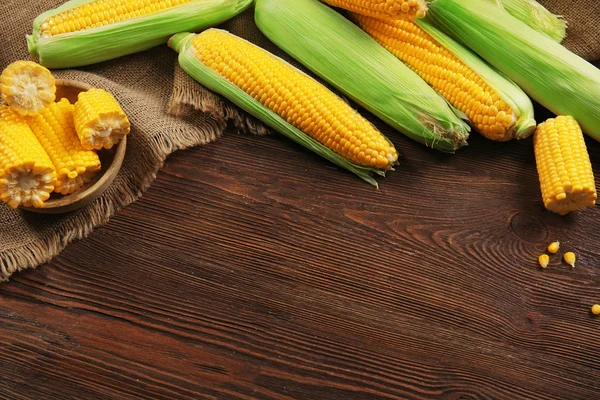 Ripe corn on sacking on wooden background — Stock Photo, Image