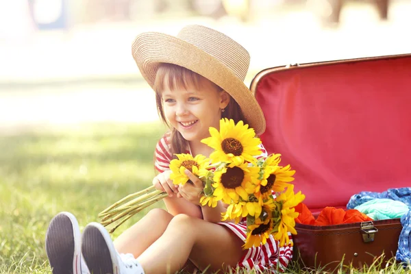 Маленькая девочка с подсолнухами и чемоданом — стоковое фото