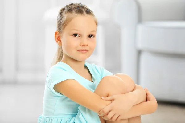 Pequena menina bonito sentado no tapete — Fotografia de Stock