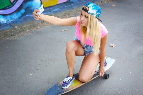 Mujer joven tomando fotos de sí misma en el monopatín — Foto de Stock