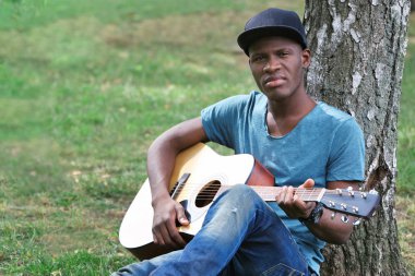  adam parkta oturup gitar ile