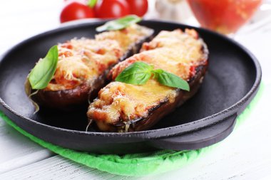 Patlıcan domates ve peynirle ahşap masa, closeup üzerinde siyah tavada tabak