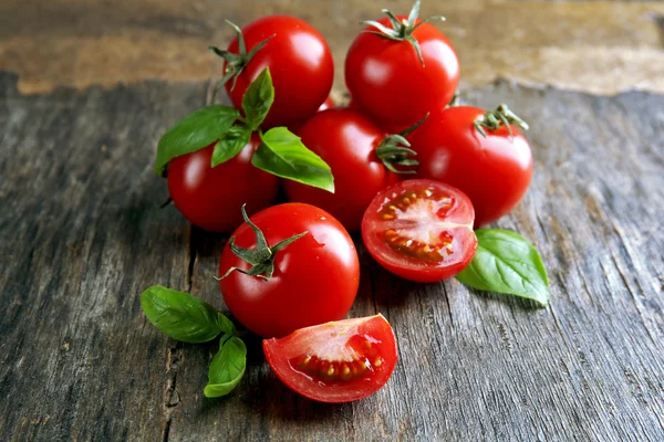 Pomidory wiśniowe z bazylią na drewnianym stole z bliska — Zdjęcie stockowe