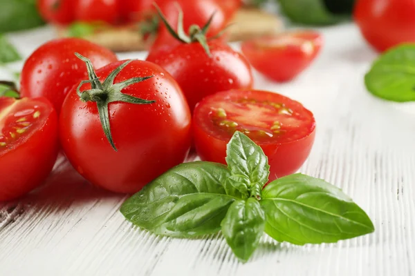 Tomates cherry con albahaca sobre mesa de madera de cerca — Foto de Stock