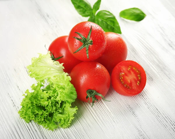 Cherry tomatoes with basil and lettuce on wooden table close up — Stock Photo, Image