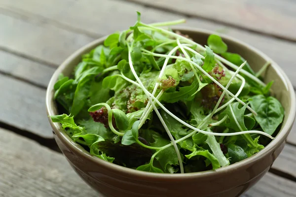 Čerstvý zeleninový míchaný salát v misce na dřevěný stůl zblízka — Stock fotografie