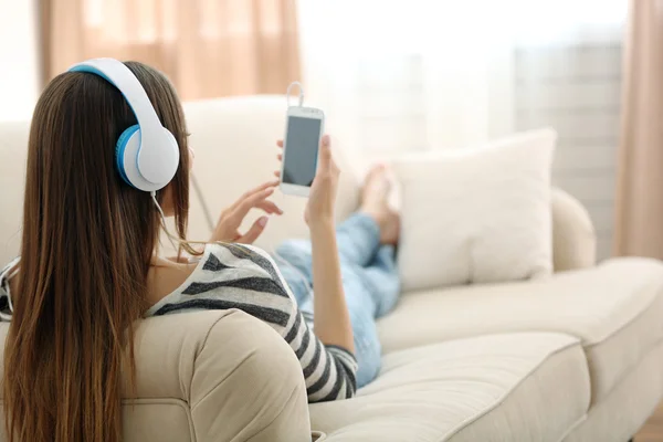 Vrouw die muziek luistert in hoofdtelefoon in de kamer — Stockfoto