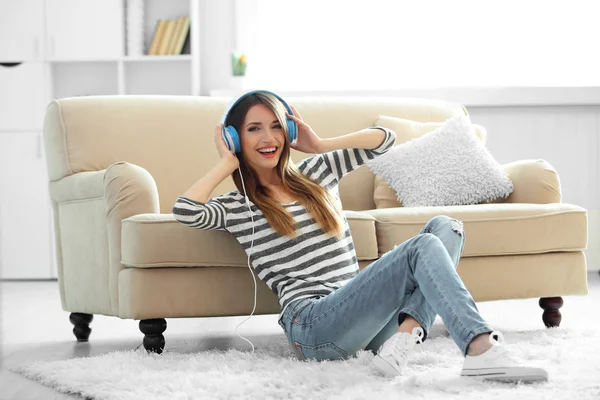 Mulher ouvindo música em fones de ouvido no quarto — Fotografia de Stock