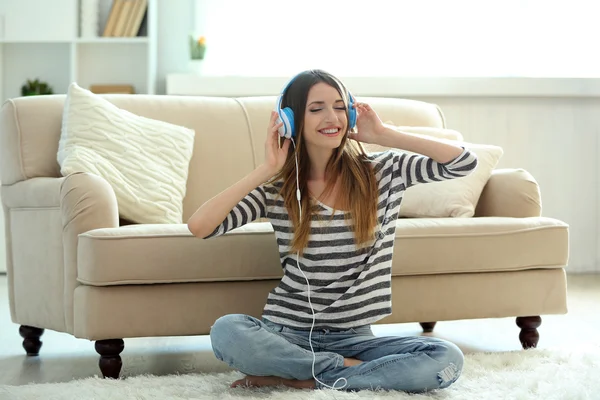 Žena poslech hudby ve sluchátkách na pokoji — Stock fotografie