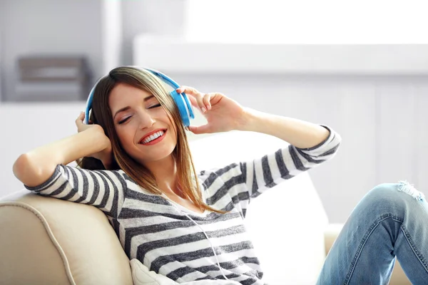 Mulher ouvindo música em fones de ouvido no quarto — Fotografia de Stock