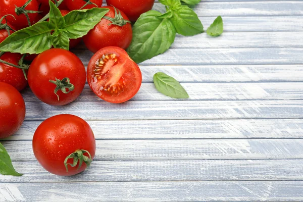 Fresh tomatoes with basil on wooden table close up — Stock Photo, Image