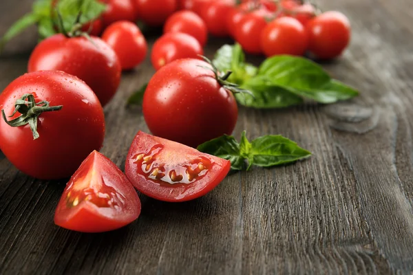 Fresh tomatoes with basil on wooden table close up — Stock Photo, Image