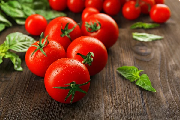 Fresh tomatoes with basil on wooden table close up — Stock Photo, Image