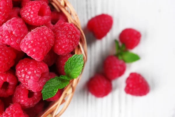 Fresh red raspberries in wicker basket on wooden table, top view — Stock Photo, Image