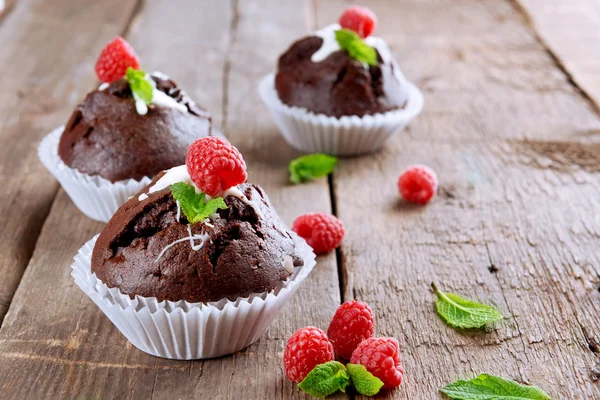 Deliziosi cupcake al cioccolato con bacche e menta fresca sul tavolo di legno da vicino — Foto Stock