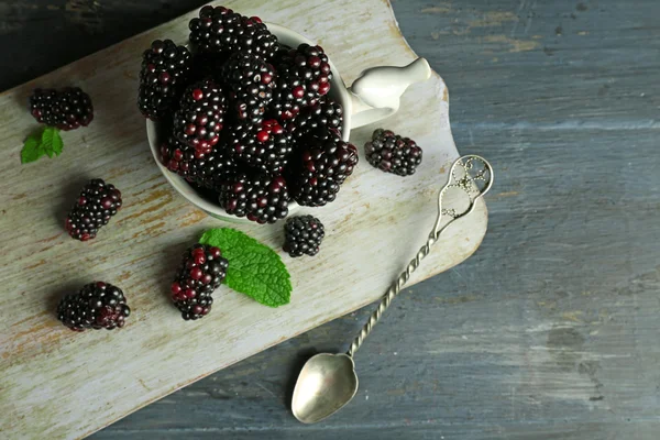 Montón de moras dulces con menta en taza en la mesa de cerca — Foto de Stock