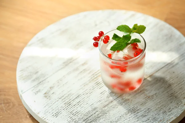 Glas kaltes erfrischendes Sommergetränk mit Beeren und Eiswürfeln auf dem Tisch in Großaufnahme — Stockfoto