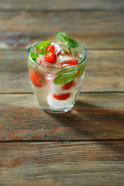 Glas kaltes erfrischendes Sommergetränk mit Beeren und Eiswürfeln auf dem Tisch in Großaufnahme — Stockfoto