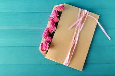 Ahşap arka plan üzerinde zarf içinde güzel güller