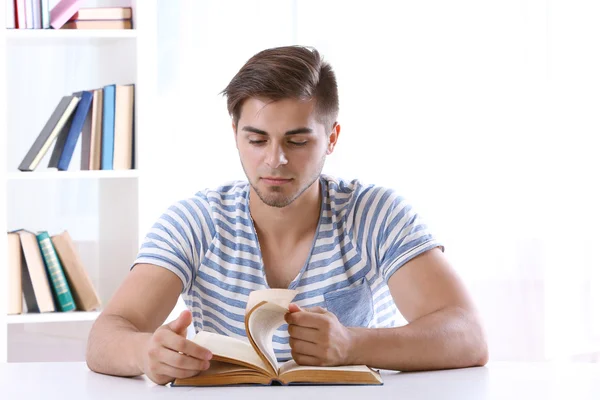 Jeune homme lisant un livre à table — Photo