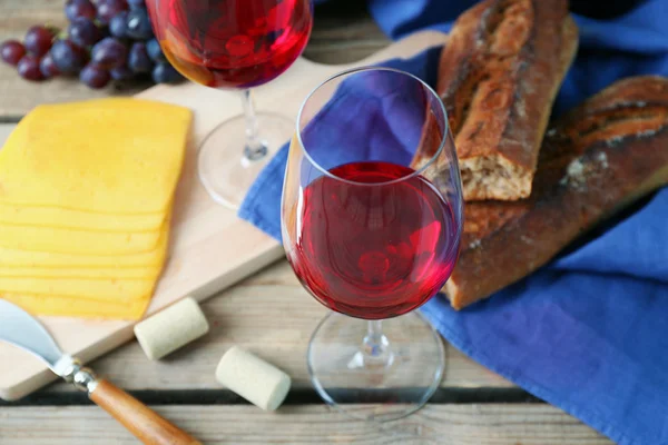 Still life of wine, grape, cheese and bread on rustic wooden background