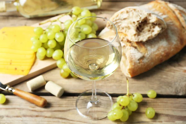 Natura morta di vino, uva, formaggio e pane su sfondo rustico in legno — Foto Stock