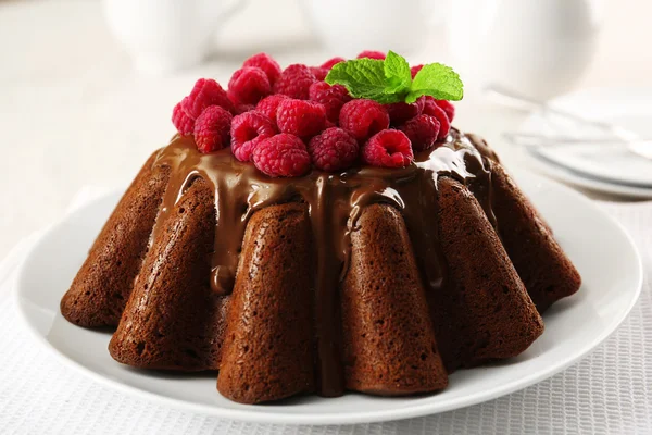 Tasty chocolate muffin with glaze and raspberries on table close up — Stock Photo, Image