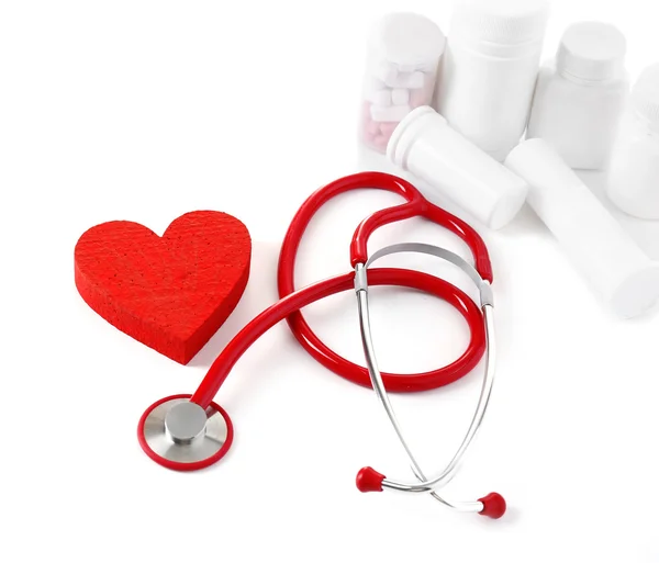 Medical stethoscope with bottles of pills and red heart isolated on white — Stock Photo, Image