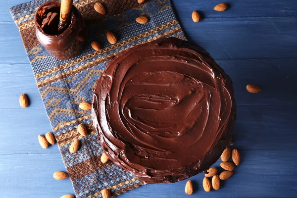 Bolo de chocolate apetitoso entre amêndoas no fundo azul — Fotografia de Stock