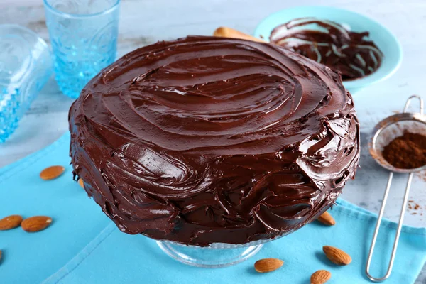Sabroso pastel bajo glaseado de chocolate sobre fondo azul claro —  Fotos de Stock