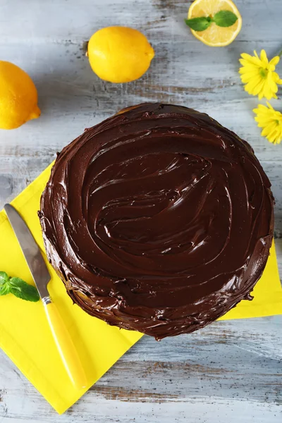 Köstlicher Schokoladenkuchen in der Nähe von Zitronen auf grauem Holztisch — Stockfoto