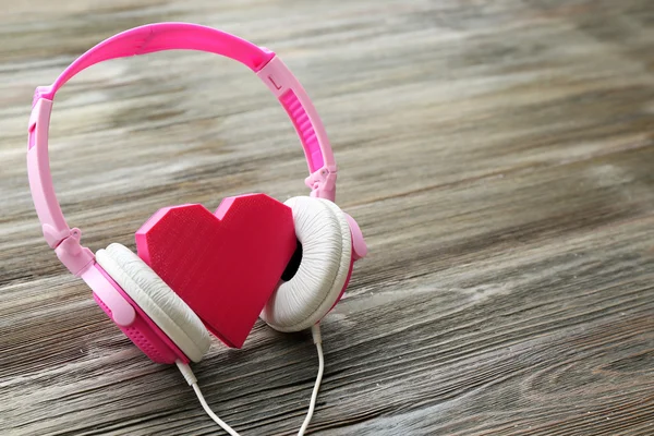Rosa Kopfhörer mit rosigem Herzen auf Holzhintergrund — Stockfoto