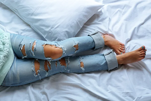 Mujer en pantalones vaqueros azules en la cama vista superior — Foto de Stock
