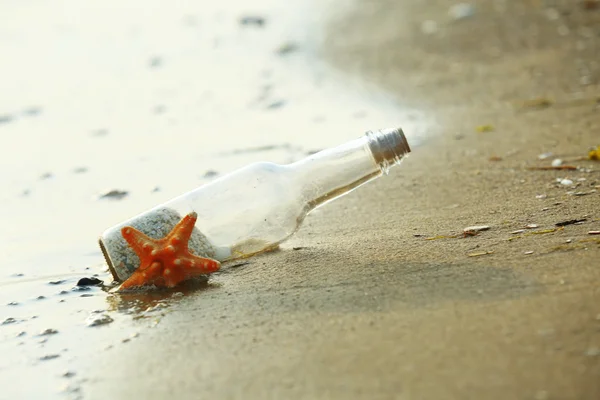 Fles met zeester op strand — Stockfoto