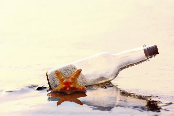 Bouteille avec étoile de mer sur la plage — Photo