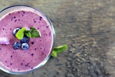 Çilek ve ahşap zemin üzerine nane ile dekore edilmiş lezzetli blueberry yoğurt