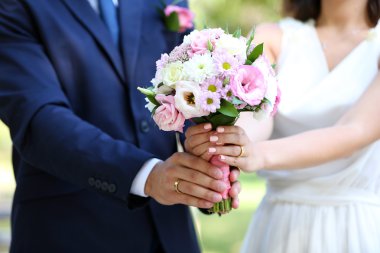 Gelin ve damat düğün buketi taşıyor.