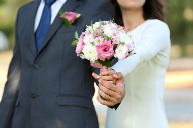 Gelin ve damat düğün buketi taşıyor.