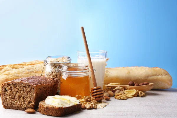 Healthy breakfast with bread, honey, nuts on table, on colorful background. Country breakfast concept — Stock Photo, Image