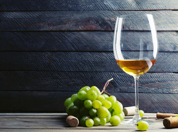 Glas Wein mit Trauben auf Holzgrund — Stockfoto