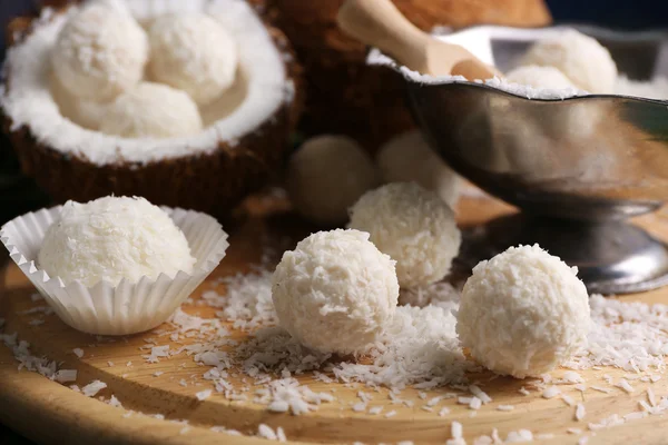 Bonbons in Kokosflocken und frischer Kokosnuss auf Holzbrett, Nahaufnahme — Stockfoto