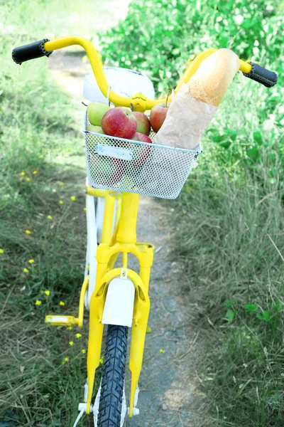 Basket of juicy fruits and bread on bike, outdoors — Stock Photo, Image