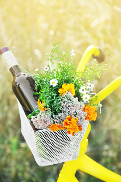 Bicycle with flowers and bottle of wine in metal basket closeup, outdoors — Stock Photo, Image