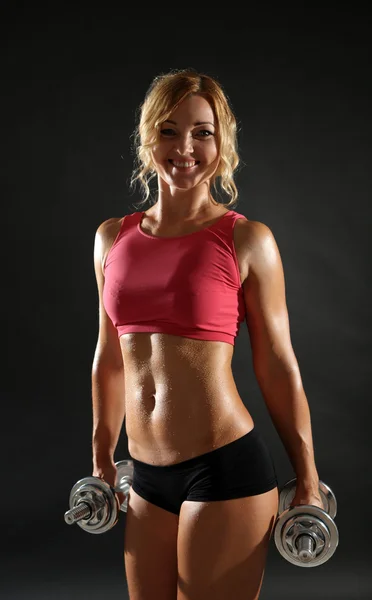 Athletic woman with dumbbells on dark background — Stock Photo, Image